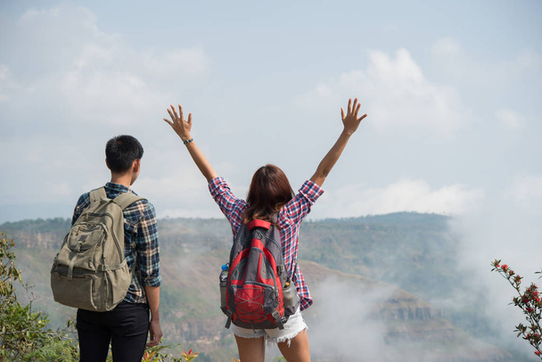 Hikers couple with backpacks standing on top of a mountain and enjoying nature view - Foto, Imagen
