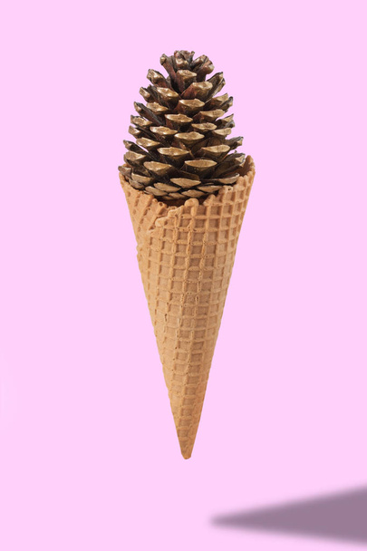 Ice cream cone with pine cone on pink background. Minimal style. - Foto, afbeelding