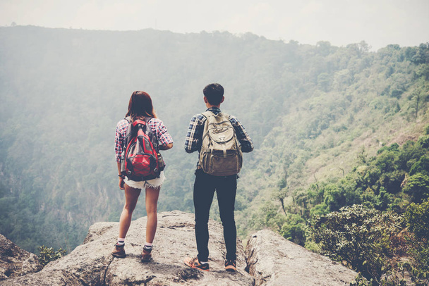 Hikers couple with backpacks standing on top of a mountain and enjoying nature view - Fotó, kép