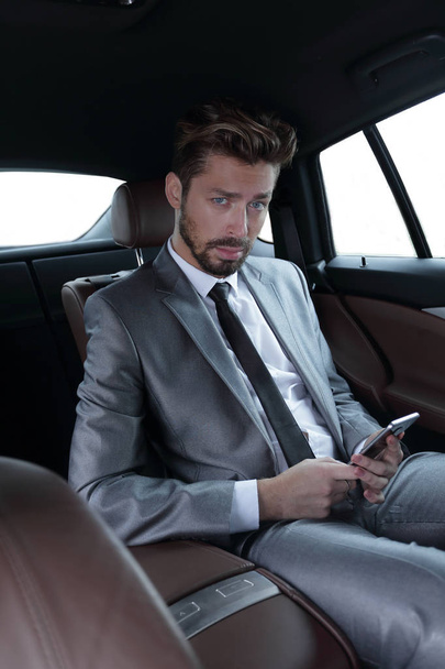 man in suit sitting in car and reading messages on smartphone - 写真・画像