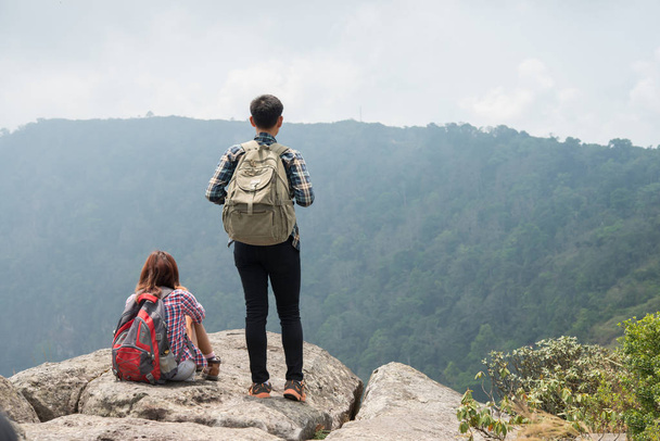Hikers couple with backpacks standing on top of a mountain and enjoying nature view - Photo, Image