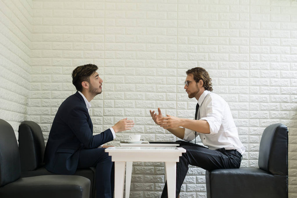 Jovem homem de negócios conversando trabalho com colega em um salão de negócios moderno. Trabalhadores das empresas
. - Foto, Imagem