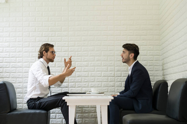 Молодой бизнесмен разговаривает с коллегой в современном бизнес-лаундже. Деловые люди
. - Фото, изображение