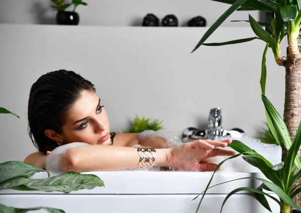 Young beautiful woman lying in bathtub and taking bath  - Foto, Imagen