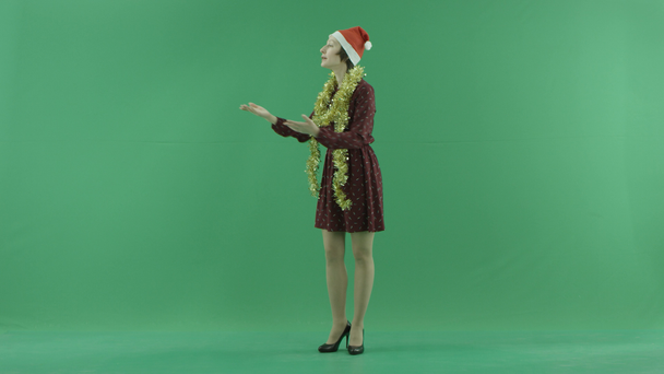 Una joven mujer de Navidad llama a alguien del lado izquierdo en la pantalla verde
 - Metraje, vídeo