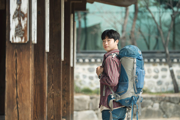 Un joven haciendo un viaje de mochilero en una casa tradicional coreana
. - Foto, imagen