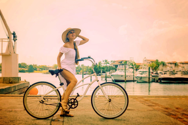 Mädchen im weißen Kleid auf einem Fahrrad am Meer - Foto, Bild