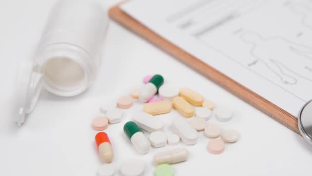 Tabletták és egy fehér üveg, a sztetoszkóppal és orvosi diagram van, mint egy fehér háttér. - Felvétel, videó
