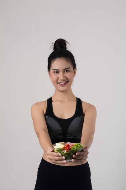 Retrato de una atractiva mujer sonriente comiendo ensalada aislada sobre fondo blanco
.  - Foto, imagen