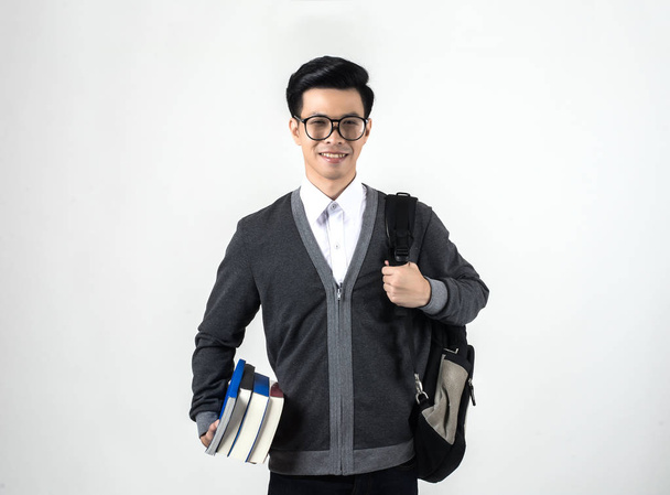 junger Nerd-Mann mit Brille hält einen Bücherstapel in der Hand, während er isoliert auf weißem Hintergrund steht - Foto, Bild