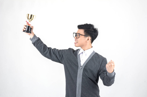 jovem nerd homem segurando um troféu e sorrindo enquanto em pé contra branco backgroun
 - Foto, Imagem