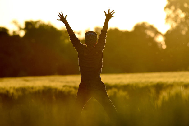 kleine jongen vrijheid springen in tarweveld bij zonsondergang - Foto, afbeelding