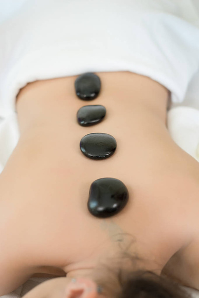 Young beautiful woman getting hot stone spa treatment - Photo, Image