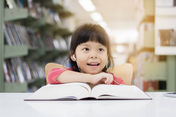 Meninas asiáticas estão lendo livros e ouvindo música na libra
 - Foto, Imagem