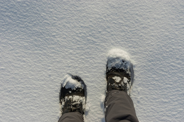 Paysage hivernal avec des jambes humaines portant des bottes et debout sur la neige fraîche profonde
 - Photo, image