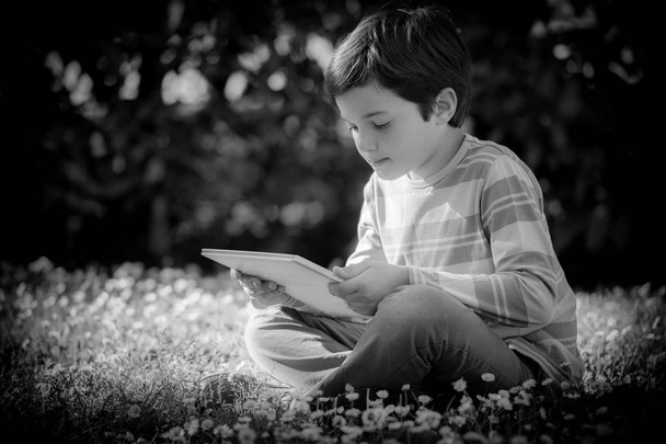Child reading a book sitting on the grass - Foto, Imagen