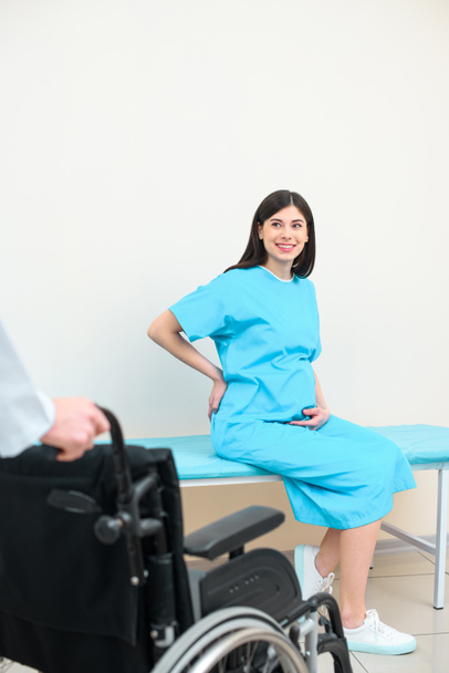беременная женщина смотрит на акушера-гинеколога с инвалидной коляской
 - Фото, изображение