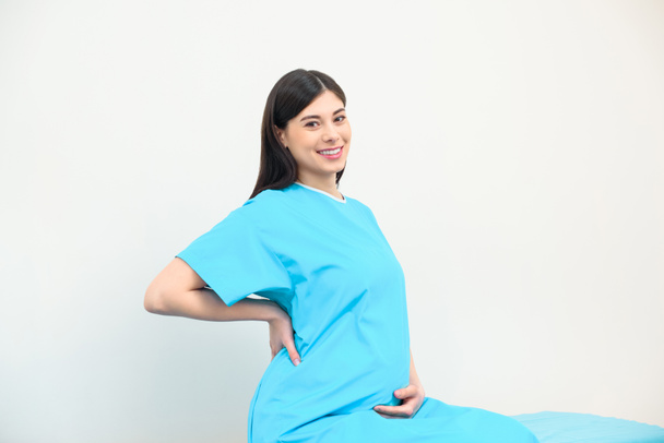 šťastná Mladá těhotná žena sedící na posteli v nemocnici - Fotografie, Obrázek