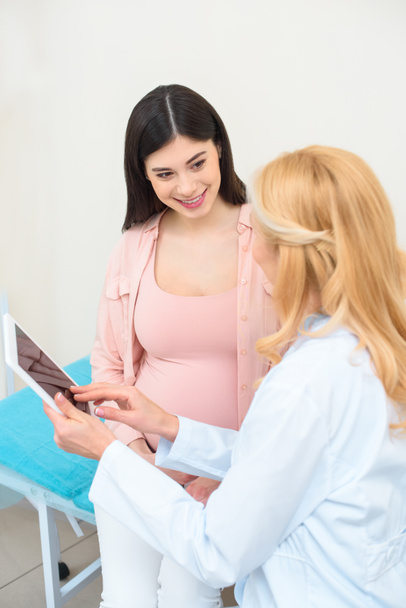 Μαιευτήρας Γυναικολόγος και νεαρή έγκυο χρησιμοποιώντας tablet μαζί - Φωτογραφία, εικόνα