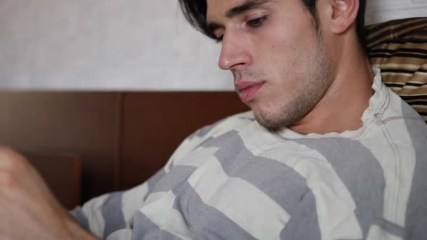 Young man lying in bed reading a book - Footage, Video