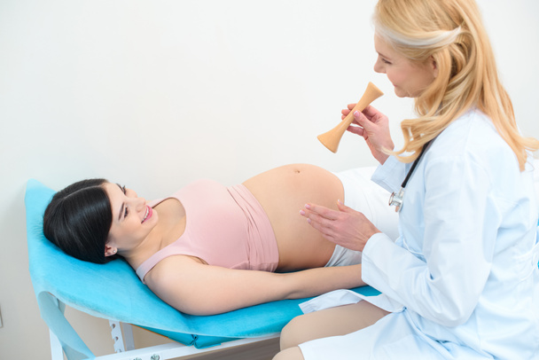 Geburtshelferin Gynäkologin mit Traube-Stethoskop und Schwangere - Foto, Bild
