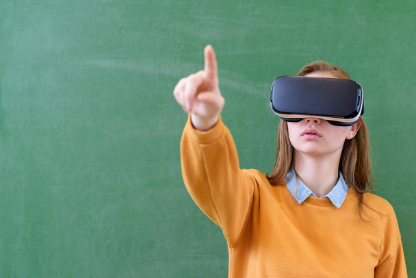 Teenager female student wearing virtual reality glasses in classroom at school. Innovative teaching methods. Education concept. - Foto, immagini