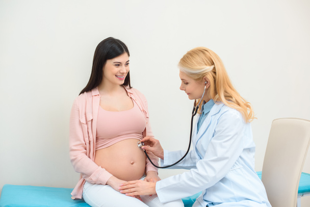 акушер-гінеколог слухає серцебиття дитини плоду вагітної жінки зі стетоскопом
 - Фото, зображення