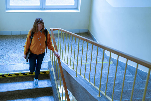 Young depressed lonely female college student walking down the stairs at her school, looking down. Education, Bullying, Depression concept. - Photo, Image