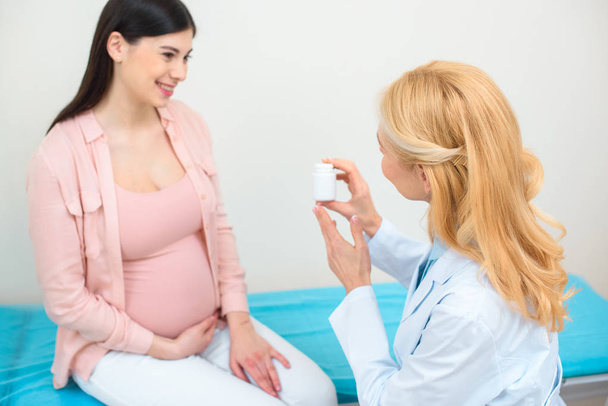 Gynäkologe zeigt Schwangeren Tablettendose - Foto, Bild