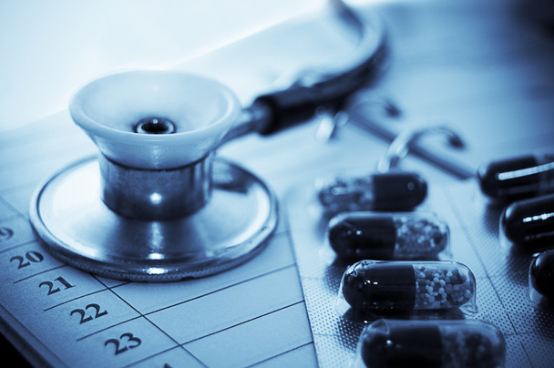 Stethoscope and pills over notebook - Photo, Image