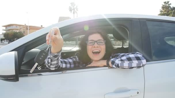 Nuori onnellinen valkoihoinen nainen näyttää uuden auton avaimen
 - Materiaali, video
