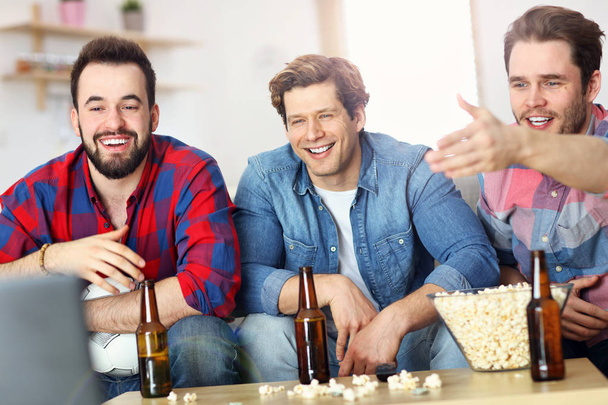 Счастливые друзья-мужчины веселятся и смотрят спорт по телевизору
 - Фото, изображение