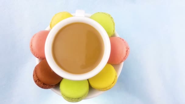 Bitterkoekjes of macaron op pastel roze oppervlak met koffie in witte kop. - Video