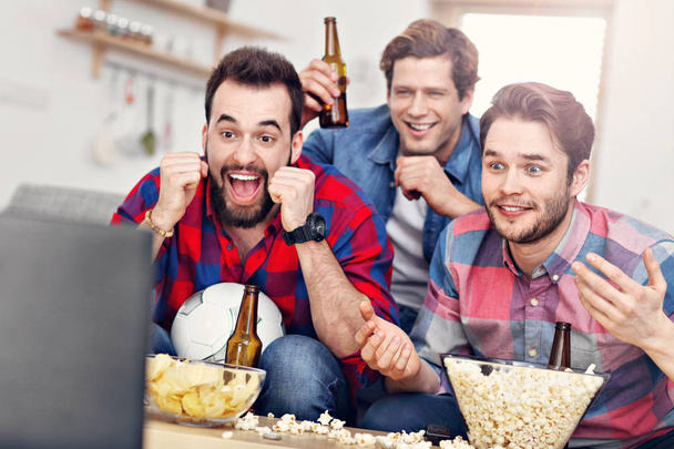 Щасливі друзі-чоловіки вітають і дивляться спорт на телебаченні
 - Фото, зображення