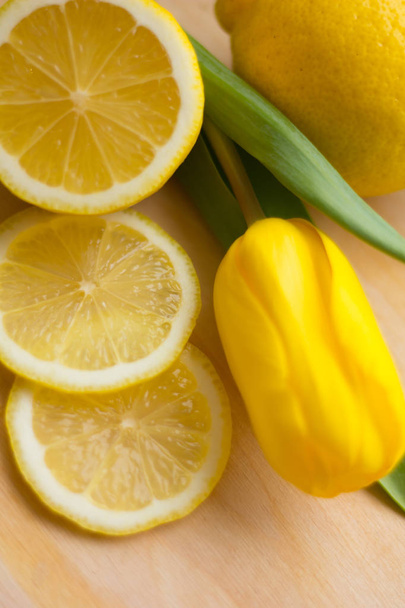 Нарізаний лимон і жовтий тюльпан на дошці
 - Фото, зображення