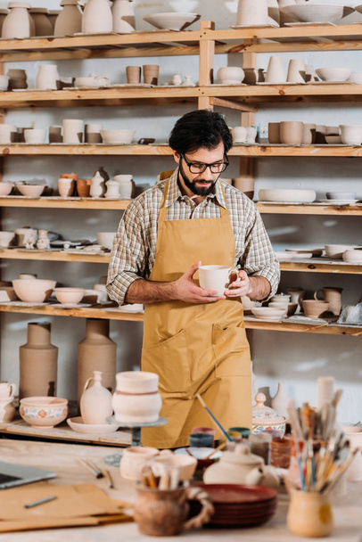 чоловічий гончар з керамічним посудом у майстерні
 - Фото, зображення