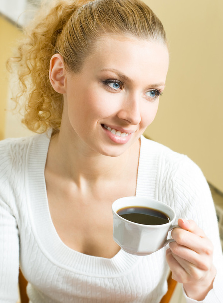 Young woman drinking coffee or tea, at home - 写真・画像
