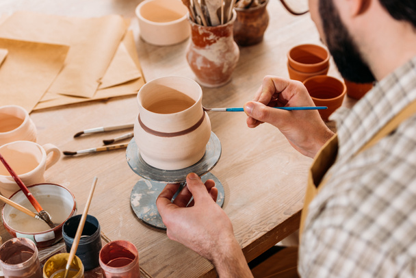 обрезанный вид гончарной живописи керамический кувшин в мастерской
 - Фото, изображение
