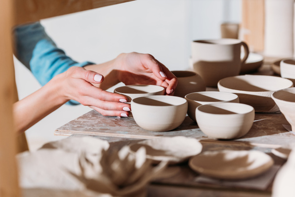Ausgeschnittene Ansicht eines Töpfers mit Keramikschalen auf Regalen in der Werkstatt - Foto, Bild