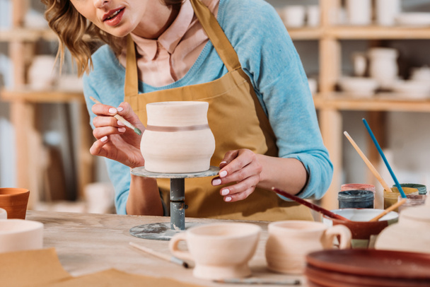 обрезанный вид женщины живописи керамической кувшин в керамической мастерской
 - Фото, изображение