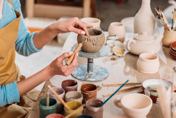 обрізаний вид жіночого гончарного прикраси керамічної чаші в майстерні
  - Фото, зображення