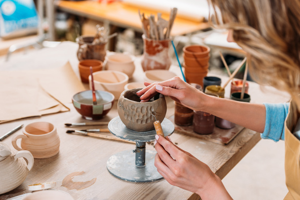 cropped view of woman decorating ceramic bowl in pottery workshop  - Photo, Image