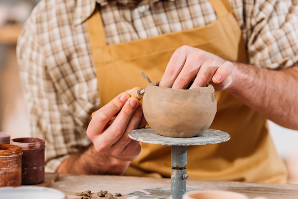 cropped view of potter making ceramic bowl in workshop - Fotó, kép