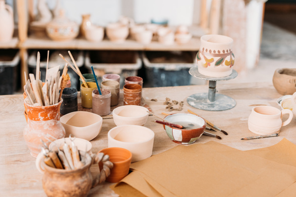 ceramics and paints on wooden table in pottery workshop - Photo, image