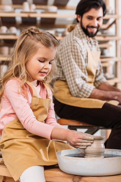 Córka, Dokonywanie ceramiczny garnek na kole garncarskim z ojcem w warsztacie - Zdjęcie, obraz