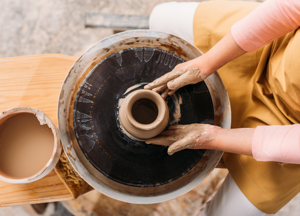 vue recadrée de l'enfant faisant pot en céramique avec de l'argile sur la roue de poterie
   - Photo, image