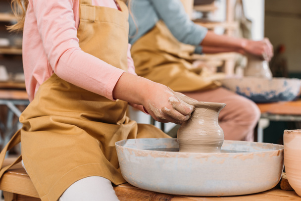 Ausgeschnittene Ansicht von Lehrer und Kind, die Töpfe aus Keramik auf Töpferscheiben herstellen - Foto, Bild