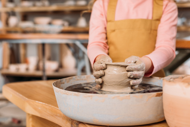 vue partielle de l'enfant faisant pot en céramique sur roue de poterie en atelier
 - Photo, image