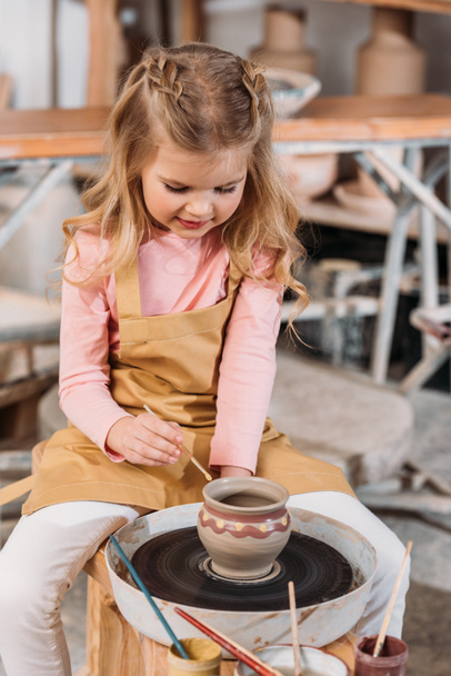 schattige blonde jongen keramische pot in workshop schilderen - Foto, afbeelding