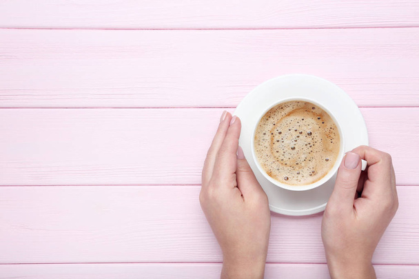 Female hands holding cup of coffee on wooden background - Φωτογραφία, εικόνα